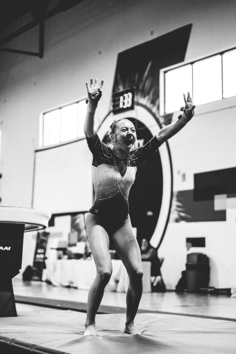 Greta Stowell performing a handstand on the uneven bars.